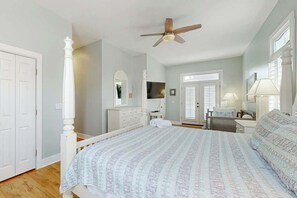 Une chambre à coucher avec un lit à baldaquin, un ventilateur de plafond, une commode, une coiffeuse et un téléviseur.