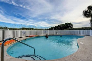 A swimming pool with a white fence, a diving board, and a person swimming. - Windcrest Villas 201 (North Myrtle Beach)
