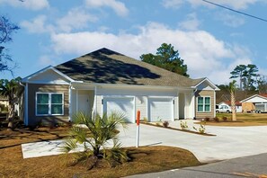 A single-story house with a garage, a front yard with a palm tree, and a clear sky. - Cocora on Church Street - A (Myrtle Beach)