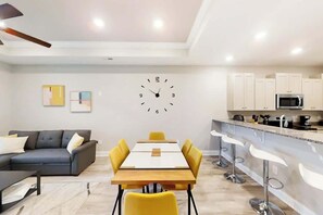 A modern living room with a sofa, a dining table, and a kitchen area with cabinets and a microwave. - Cocora on Church Street - A (Myrtle Beach)