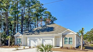Einbungalow mit Garage, ein Vorgarten mit einer Palme und einem strahlend blauen Himmel.