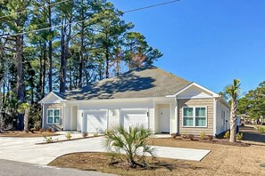 A single-story house with a garage, a front yard with a palm tree, and a clear blue sky. - Cocora on Church Street - B (Myrtle Beach)