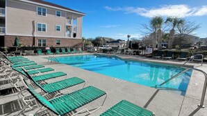 A swimming pool with lounge chairs and a building in the background. - Cypress Bend Unit 432 (North Myrtle Beach)