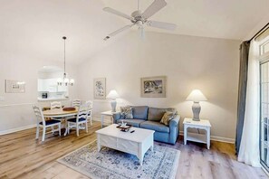 A living room with a ceiling fan, a dining table with chairs, a sofa, a coffee table, and two lamps. - Cypress Bend Unit 432 (North Myrtle Beach)