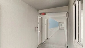 A long, narrow hallway with doors on one side and windows on the other. - Ocean Vibes Beach Retreat (Murrells Inlet)