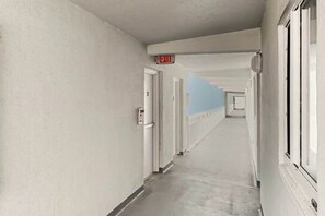 Ein langer, schmaler Korridor mit Türen auf der einen Seite und Fenstern auf der anderen.
