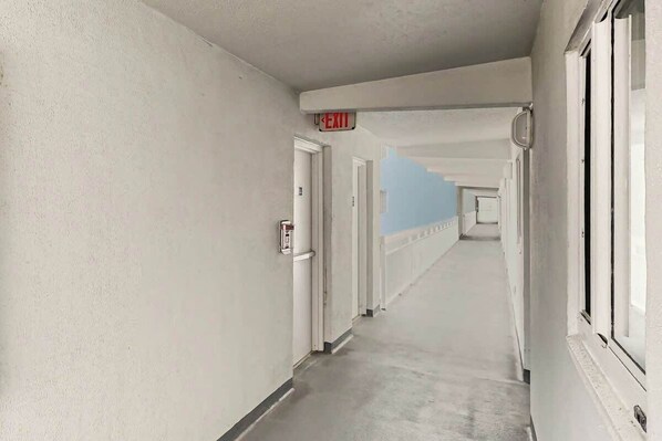 A long, narrow hallway with doors on one side and windows on the other. - Ocean Vibes Beach Retreat (Murrells Inlet)