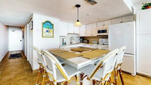 A kitchen with white cabinets, a white refrigerator, and a dining area with a table and chairs. - Ocean Vibes Beach Retreat (Murrells Inlet)