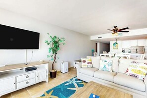 A living room with a flat-screen TV, a coffee table, a sofa, a ceiling fan, and a potted plant. - Ocean Vibes Beach Retreat (Murrells Inlet)