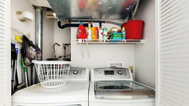 A compact laundry area with two washing machines, a drying rack, and a shelf with cleaning supplies. - Ocean Vibes Beach Retreat (Murrells Inlet)