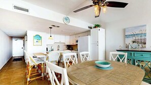A modern kitchen with white cabinets, a dining area with a round table, and a ceiling fan. - Ocean Vibes Beach Retreat (Murrells Inlet)
