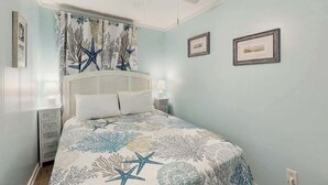 A bedroom with a bed, a nightstand, a ceiling fan, and wall-mounted artwork. - Myrtle Beach Resort  A-306 (Myrtle Beach)