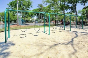 Ein Spielplatz mit Schaukeln und Sandkasten.