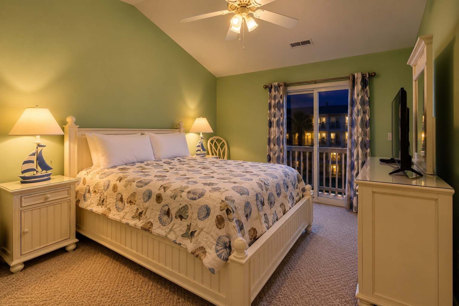 A bedroom with a bed, nightstands, a ceiling fan, a balcony with curtains, and a television.