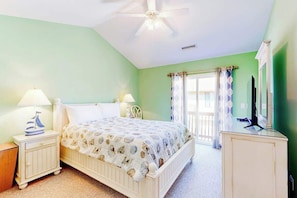 A bedroom with a bed, nightstands, a ceiling fan, and a television. - The Singing Gull Retreat (Myrtle Beach)