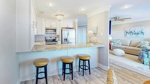 A modern kitchen with white cabinets, a marble countertop, and a central island with stools. - *Hook Wine and Sinker (Surfside Beach)