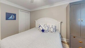 A bedroom with a bed, a wardrobe, a ceiling fan, and a wall-mounted artwork. - *Hook Wine and Sinker (Surfside Beach)