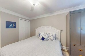 Ein Schlafzimmer mit einem Bett, einem Kleiderschrank, einem Deckenventilator und einem an der Wand hängenden Kunstwerk.