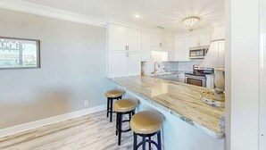 A kitchen with white cabinets, a marble countertop, and three stools. - *Hook Wine and Sinker (Surfside Beach)