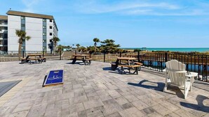 Eine Terrasse im Freien mit Picknicktischen und einer Fahrradtafel mit Blick auf ein Gewässer.