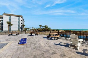 Eine Terrasse im Freien mit Picknicktischen und einer Fahrradtafel mit Blick auf ein Gewässer.