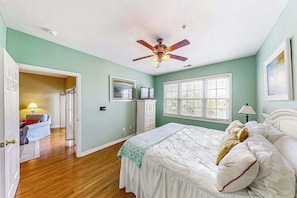 A bedroom with a bed, a ceiling fan, a window, and a door leading to another room. - Ocean Keyes 3722 The Gleaming Starfish (North Myrtle Beach)