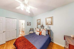 A bedroom with a bed, a ceiling fan, a door, and a nightstand. - Ocean Keyes 3722 The Gleaming Starfish (North Myrtle Beach)