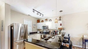 Een moderne keuken met roestvrijstalen apparatuur, een centraal kookeiland met zitplaatsen en een decoratieve vaas.
