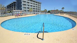 A swimming pool with a 3 FT depth marker, surrounded by a sandy beach and a multi-story building in the background. - The Golden Sailboat B-139 (Myrtle Beach)