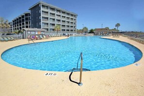 A swimming pool with a 3 FT depth marker, surrounded by a sandy beach and a multi-story building in the background. - The Golden Sailboat B-139 (Myrtle Beach)