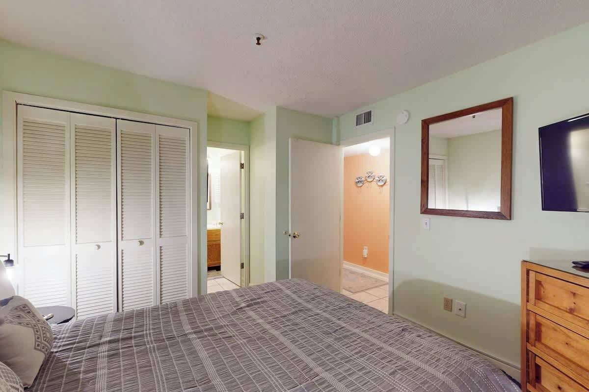 Une chambre à coucher comprenant un lit, une commode, un miroir et un placard avec des portes coulissantes.