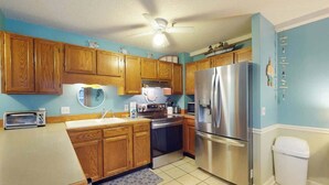 A kitchen with wooden cabinets, a stainless steel refrigerator, a microwave, and a toaster. - The Golden Sailboat B-139 (Myrtle Beach)