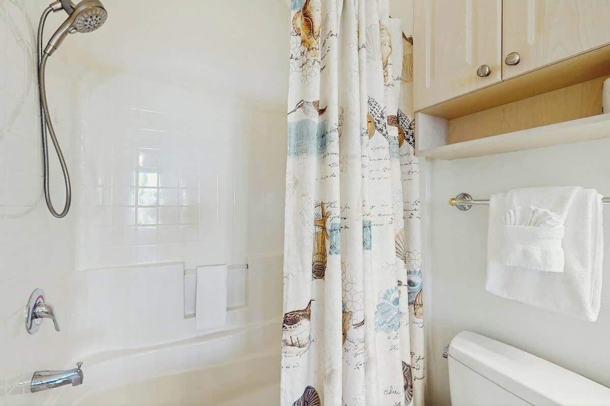 A bathroom with a shower, a toilet, and a towel rack.
