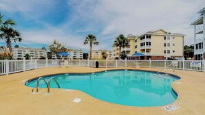 A swimming pool with a white fence, surrounded by multi-story buildings with balconies. - Turtle Cove Unit #204 (Myrtle Beach)