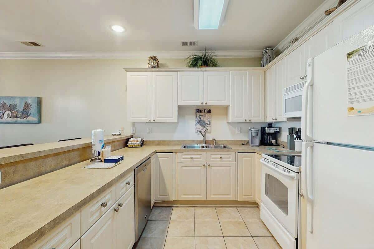 A kitchen with white cabinets, a microwave, a refrigerator, and a sink.
