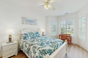 A bedroom with a bed, nightstands, a desk, and a ceiling fan. - Turtle Cove Unit #204 (Myrtle Beach)