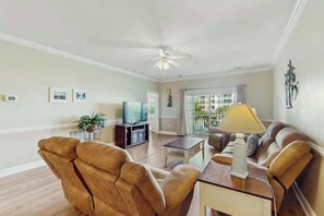 Ein Wohnzimmer mit einer Couch, einem Couchtisch, einem Fernseher und einem Deckenventilator.