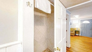A hallway with a door leading to a bathroom with tiled walls and a shower area. - Seahorse Serenity Retreat (North Myrtle Beach)