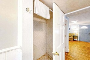 A hallway with a door leading to a bathroom with tiled walls and a shower area. - Seahorse Serenity Retreat (North Myrtle Beach)