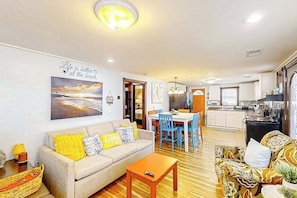 A living room with a sofa, a coffee table, and a dining area with a table and chairs. - Seahorse Serenity Retreat (North Myrtle Beach)