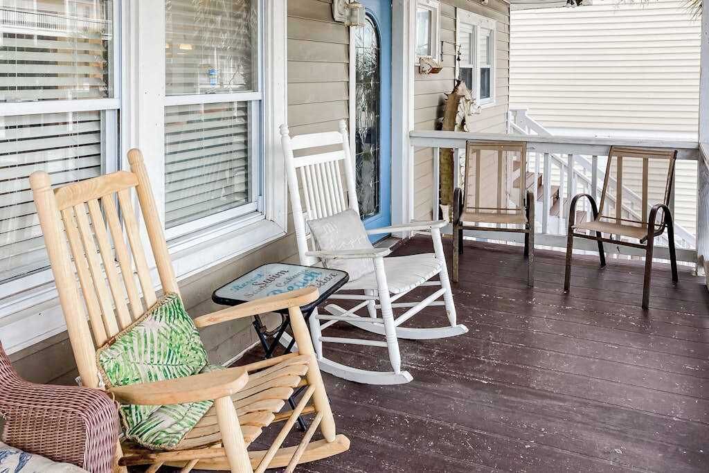 Een veranda met schommelstoelen, een tafel en een bank.