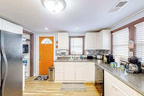 A compact kitchen with white cabinets, a sink, a stove, and a refrigerator. - Seahorse Serenity Retreat (North Myrtle Beach)