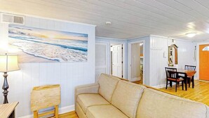 A living room with a beige sofa, a wooden coffee table, and a painting of a beach scene. - Seahorse Serenity Retreat (North Myrtle Beach)