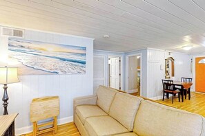 A living room with a beige sofa, a wooden coffee table, and a painting of a beach scene. - Seahorse Serenity Retreat (North Myrtle Beach)