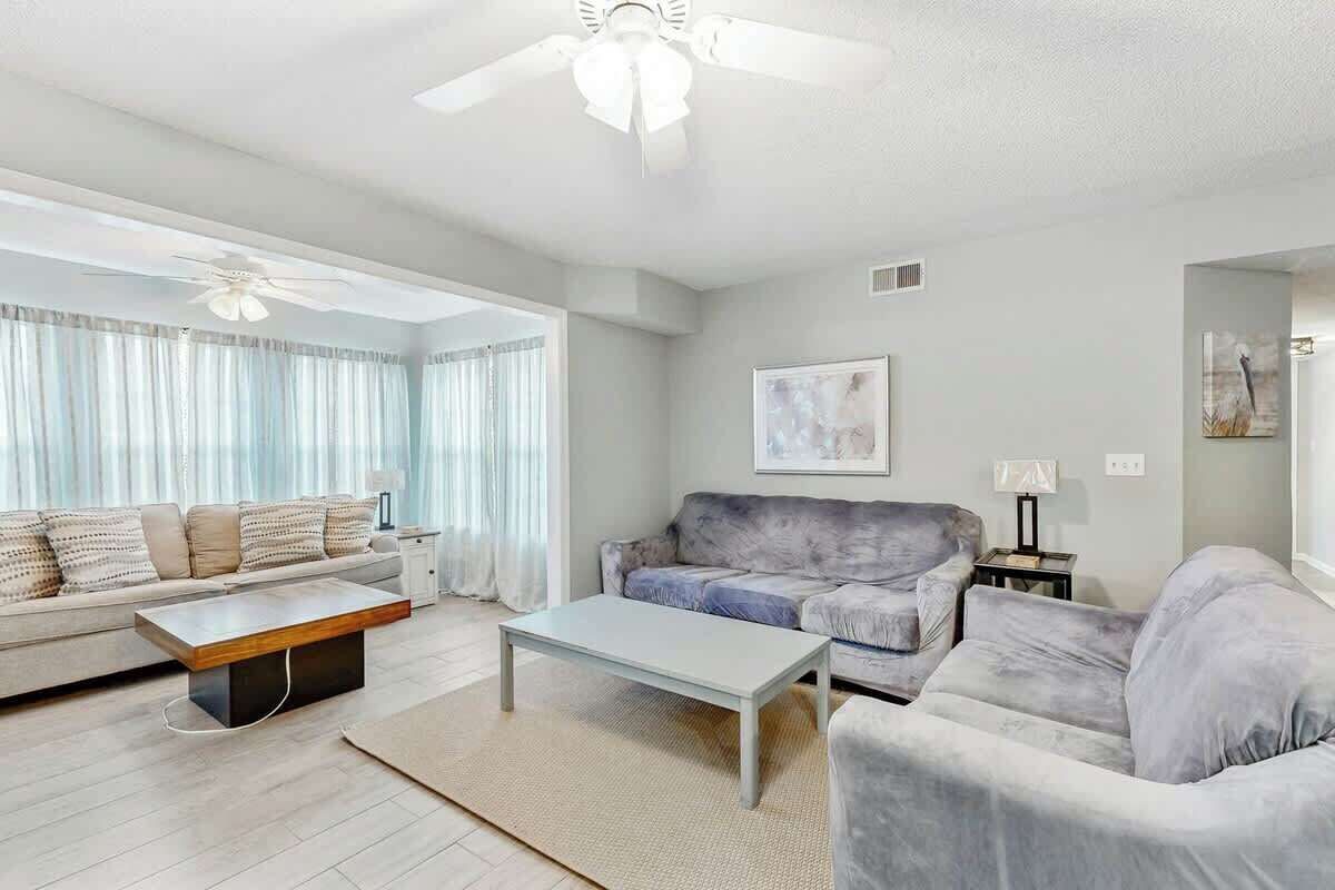 A modern living room with a sofa, a coffee table, and a ceiling fan.