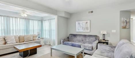A modern living room with a sofa, a coffee table, and a ceiling fan.