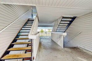 A narrow, enclosed stairwell with metal railings and a concrete floor. - Sunny Shores Retreat (Myrtle Beach)