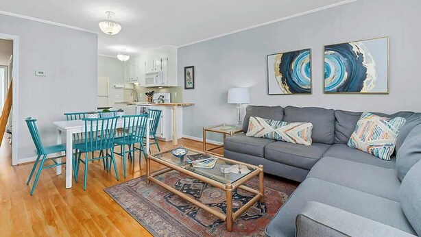 A modern living room with a grey sofa, teal chairs, a glass coffee table, and abstract wall art. - Inlet Point Villas 10-D (North Myrtle Beach)