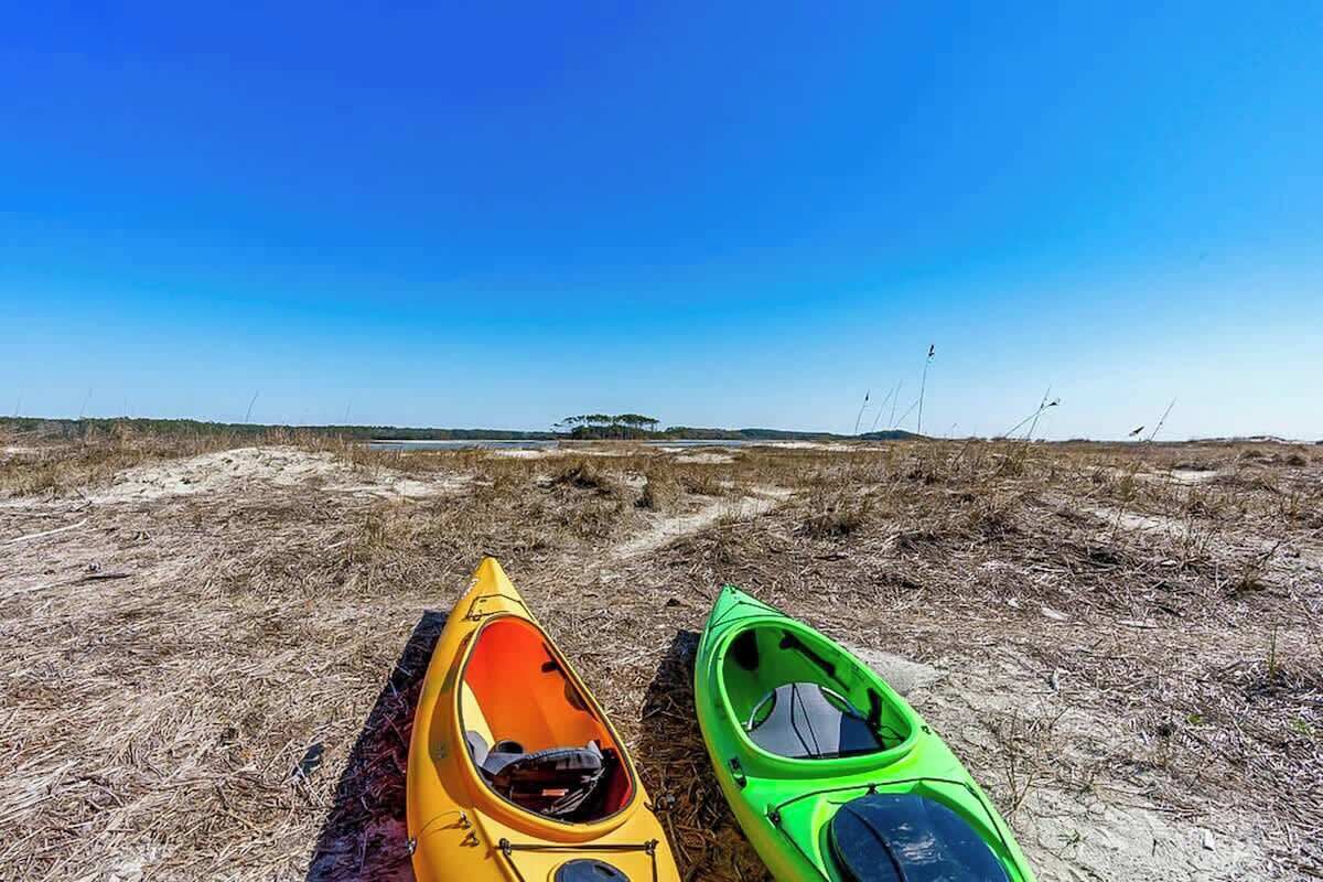 Zwei Kajaks am sandigen Strand bei blauem Himmel.