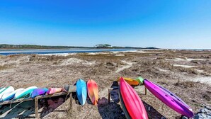 A row of colorful kayaks on a wooden stand by a beach with a clear sky. - Inlet Point Villas 10-D (North Myrtle Beach)